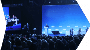 Publikum bei Konferenz vor großer Bühne
